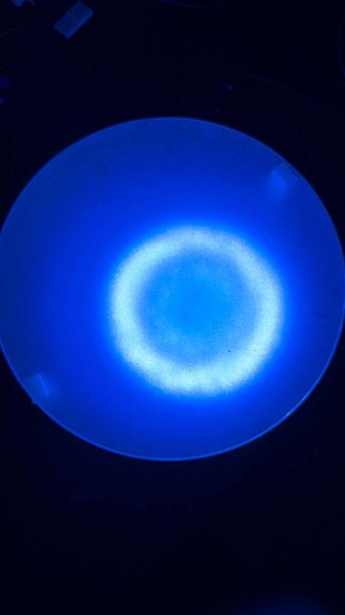 Frosted glass lit from below, a soft ring of white on blue with no single LEDs visible