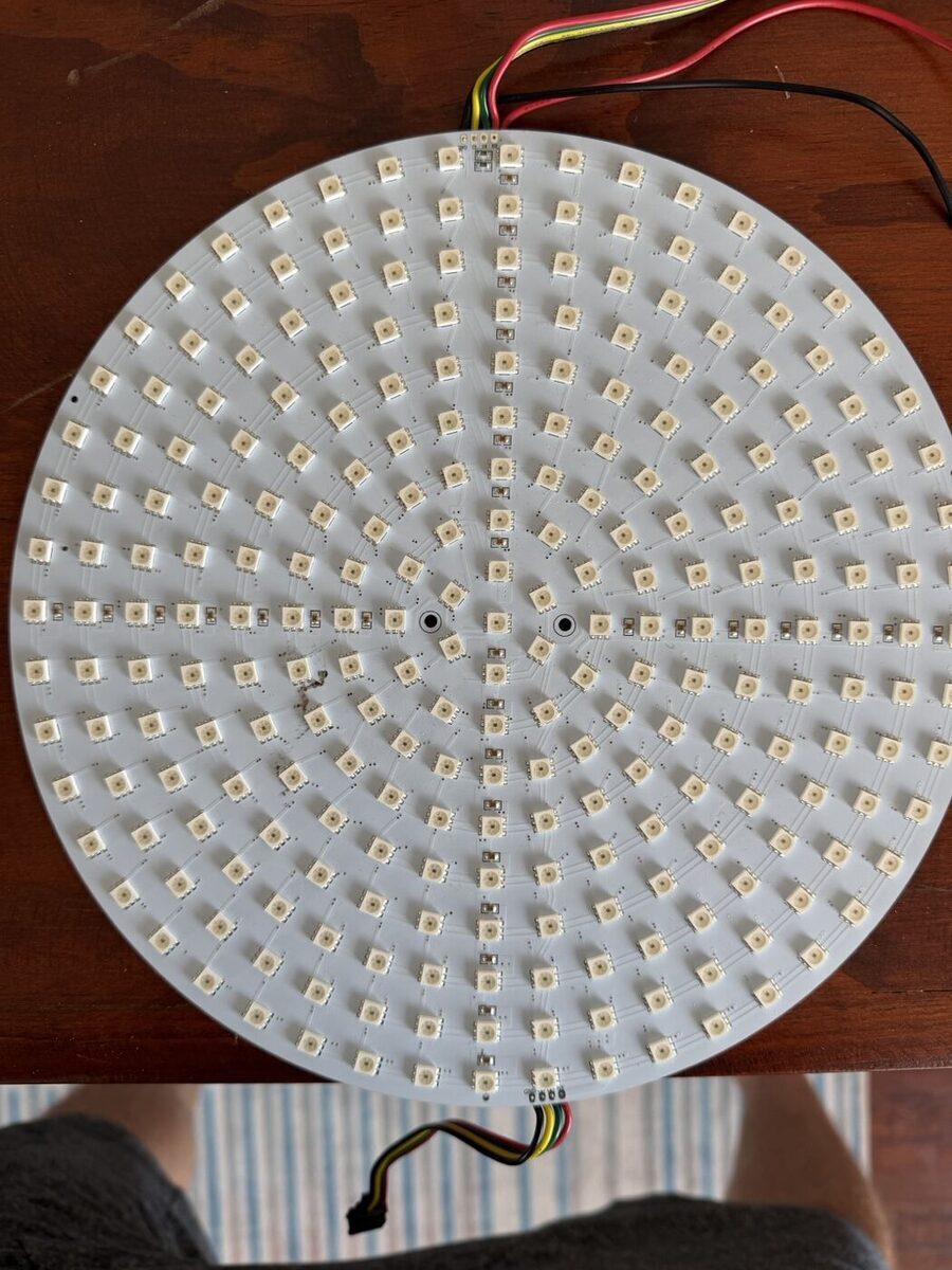 A round white circuit board covered in rings of small LEDs