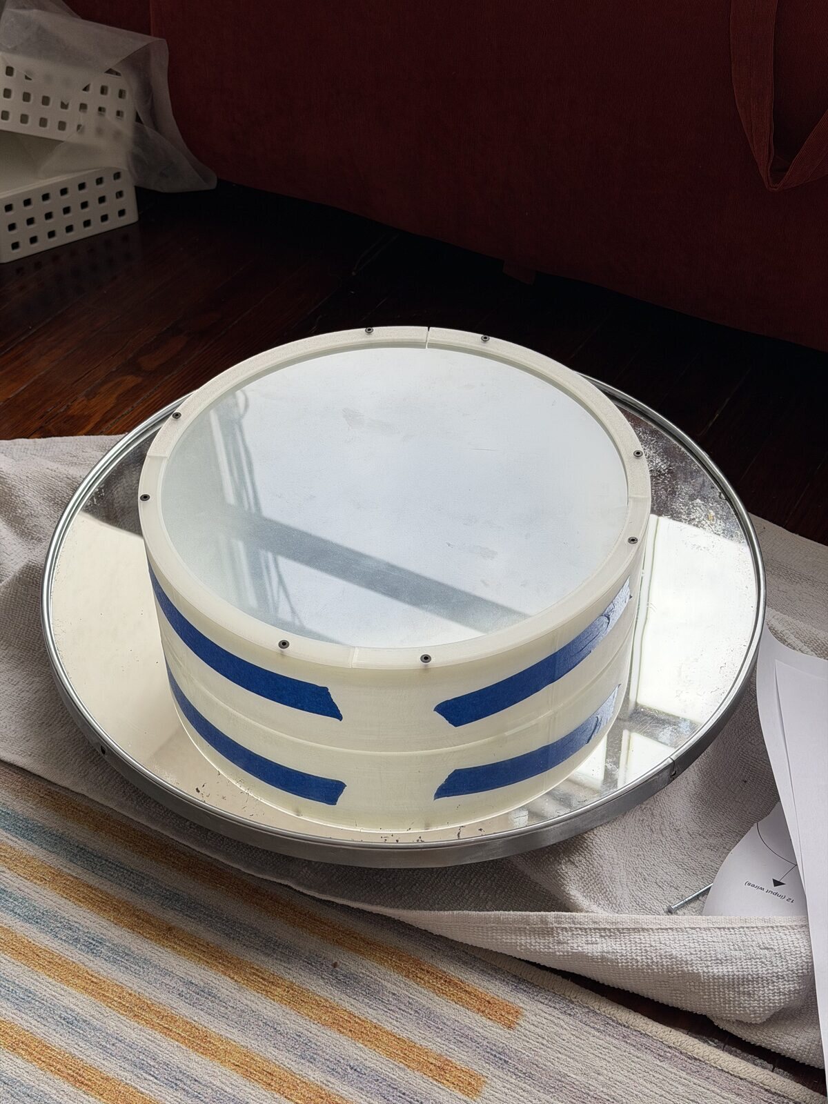The clear wall and glass standing on the round mirror, tape on the seams