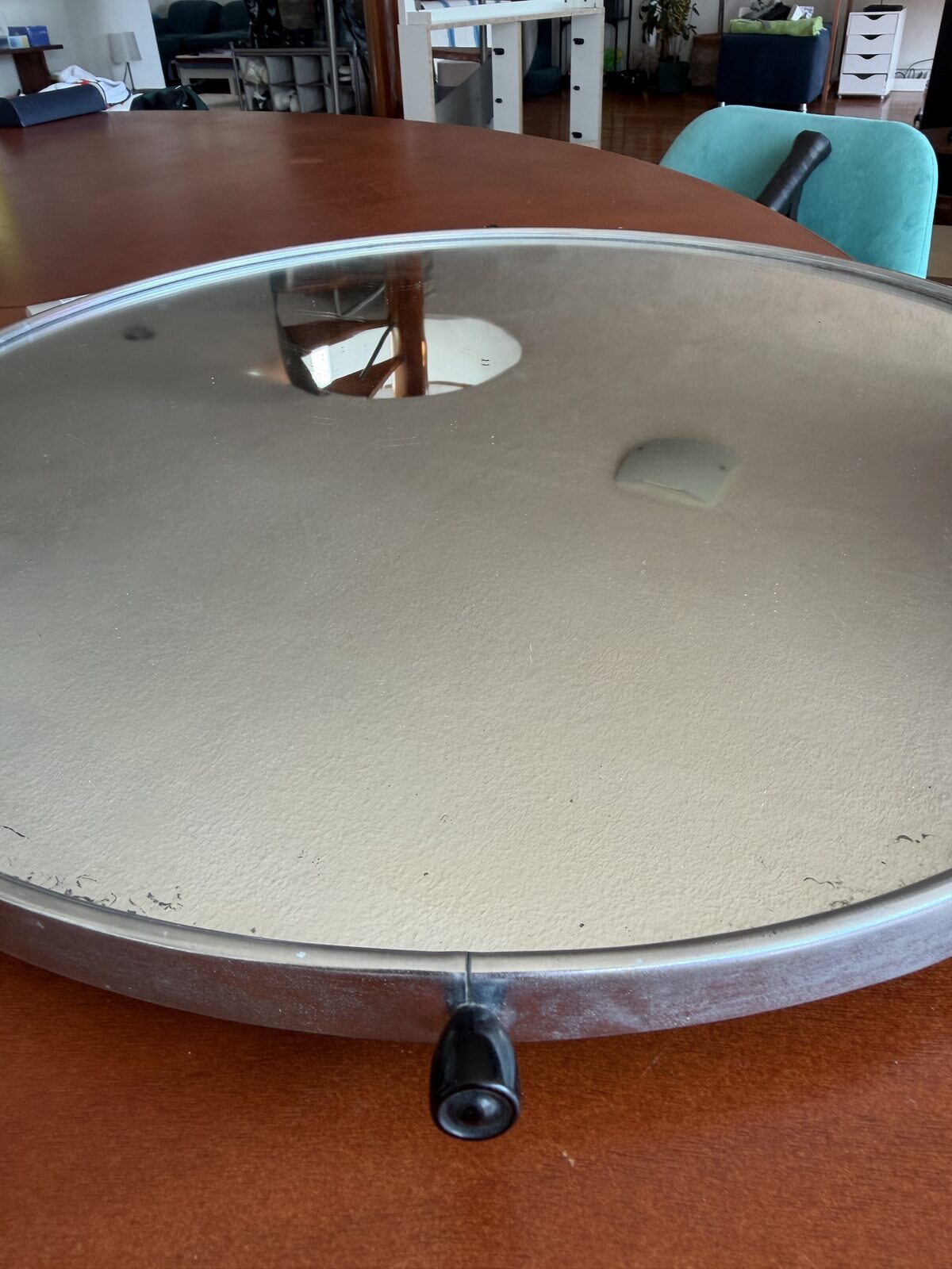 A round mirror in a black steel pan