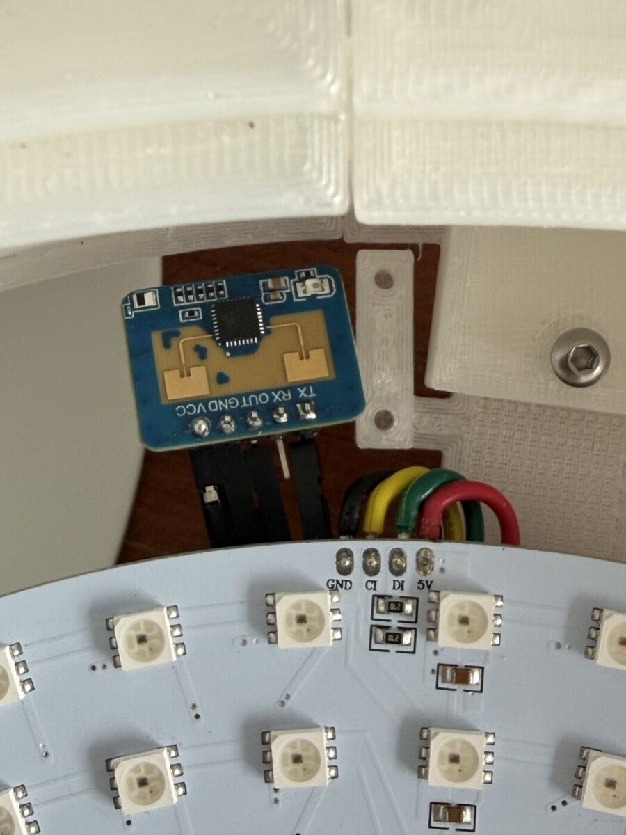 A small blue radar board laid at the edge of the LED disk, beside its input wires