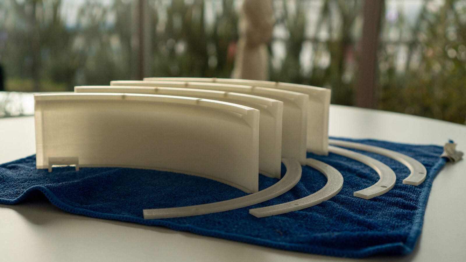 Four curved clear wall pieces and four thin ring pieces laid out on a blue towel