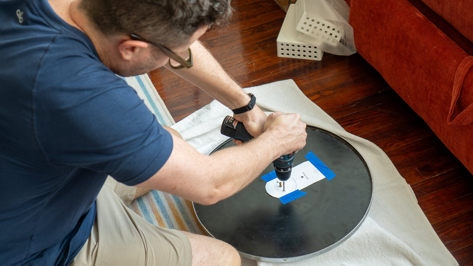 Dan drilling through a paper template taped to the back of the mirror