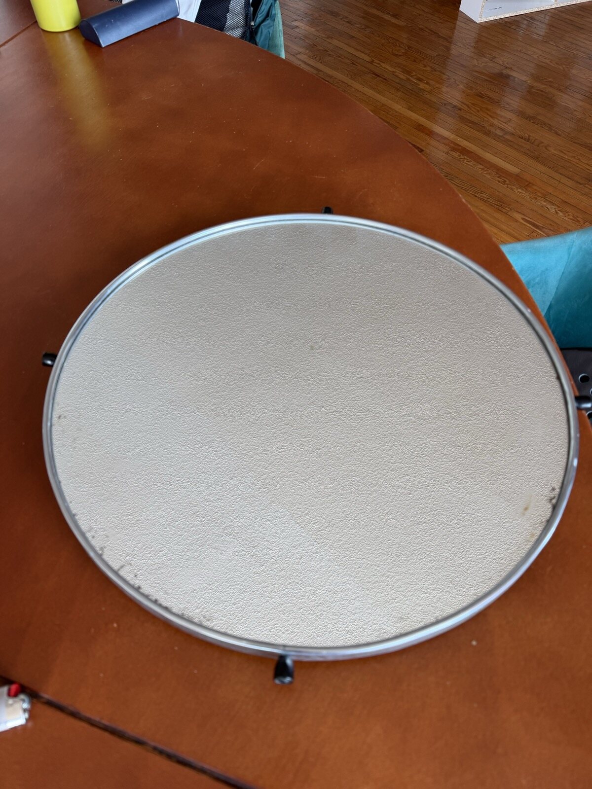 A round mirror in a black steel pan, held up by hand